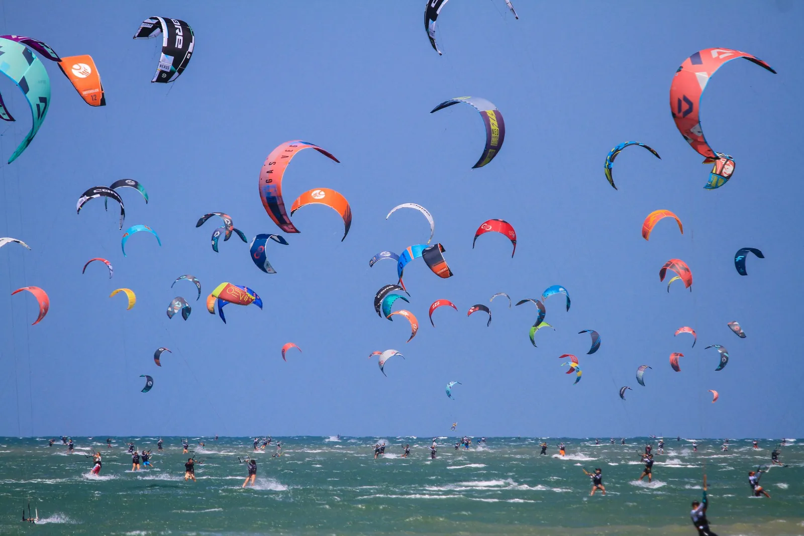 Dezenas de velas de kitesurf coloridas sobre o mar do Ceará