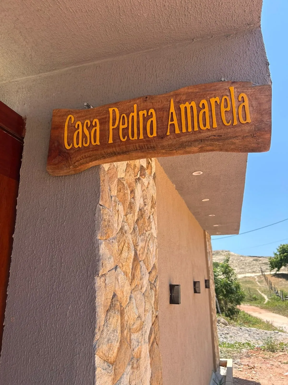 Placa de madeira da Casa Pedra Amarela na entrada da casa